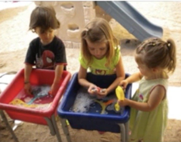 Preschool children playing together at an activity table.