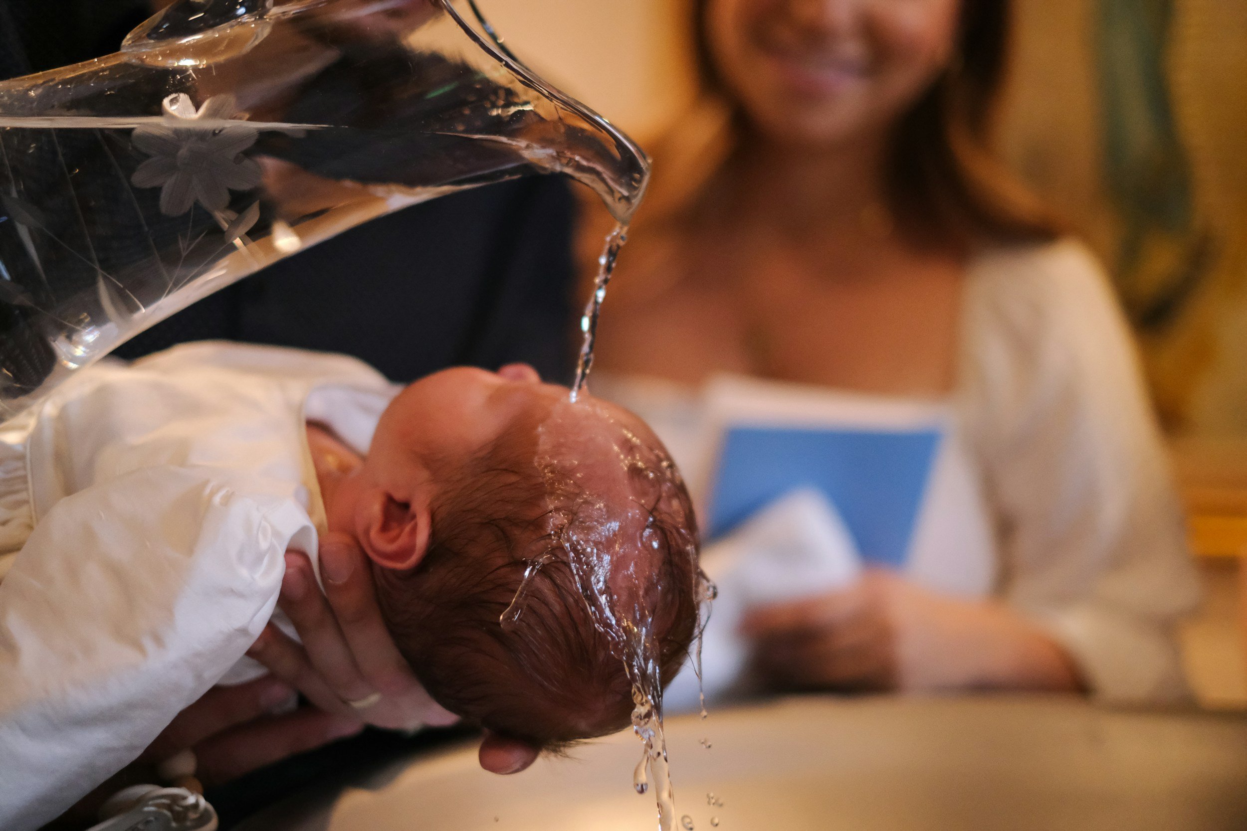 Water being poured over a baby’s head at Baptism.