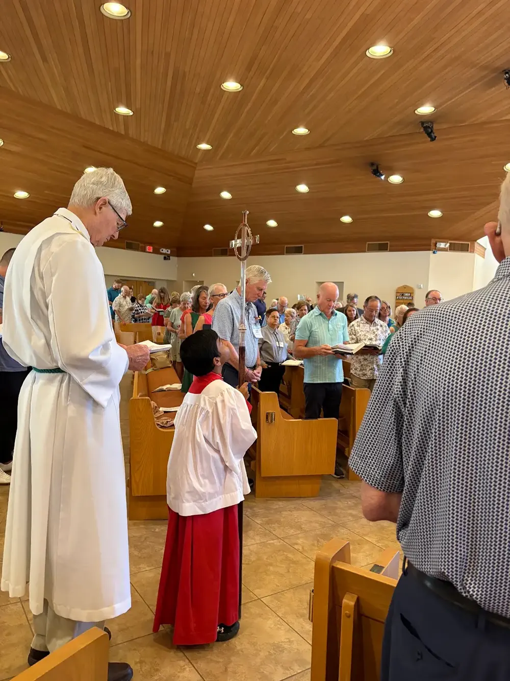 A young person taking part in worship alongside clergy.