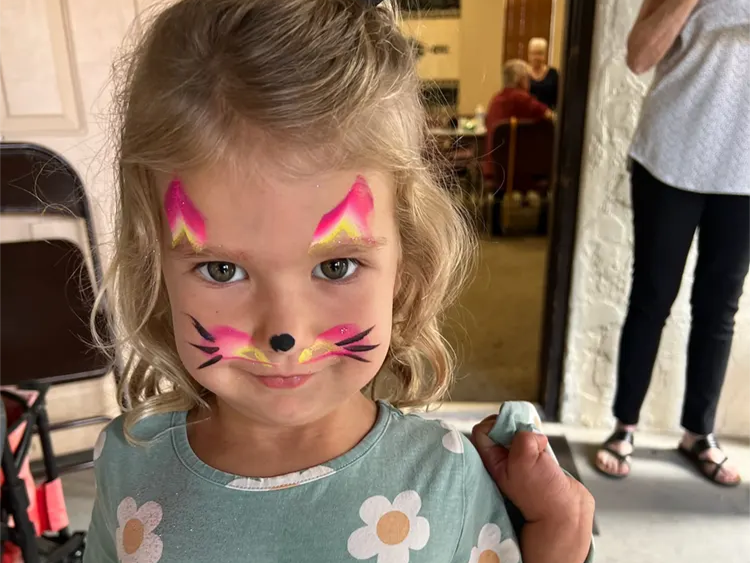 A child with a painted cat face at a parish gathering.
